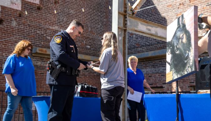 K-9 Faust is honored at the We Ride to Provide (WRTP) K-9 Memorial. His handler, BNSF Senior Special Agent Bryan Schaffer, accepts the award. 