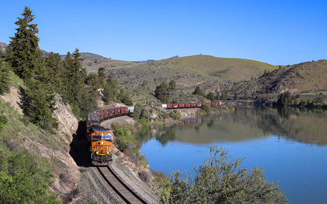 A BNSF Tier 4 locomotive leads a grain train along the Flathead River.